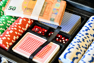 Poker chips, dice, stack of euro banknotes before playing cards.