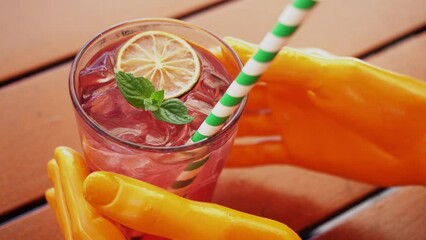 Hand of mannequin or robot takes glass with a pink refreshing drink with ice cubes, lemon and mint leaves. Concept robotic manipulator. Artificial intelligence. Wooden table. Cafe or restaurant. Food - Powered by Adobe