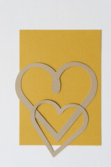 two paper hearts on yellow ochre and light beige paper