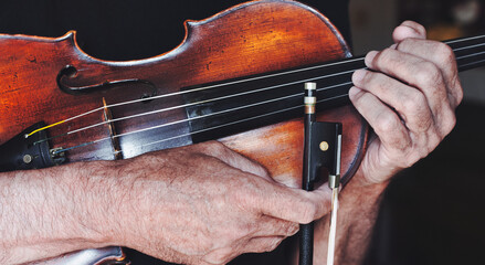 An old violin and a bow in the hands of a violinist.