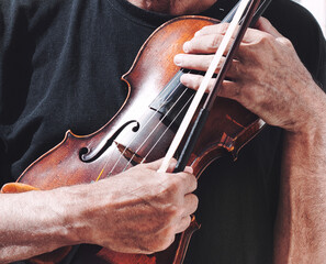 An old violin and a bow in the hands of a violinist.