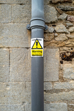 Anti Climb Paint warning sign seen attached to a newly painted wrought iron drainpipe seen on a church exterior.