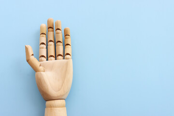 Wooden figure hand on blue background. Copy space