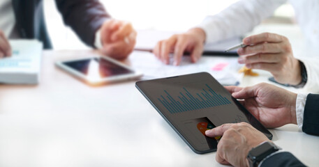 Group of business people working on a project, using digital tablet brainstorming, analyzing graph and business growth at office.
