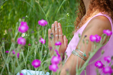 close up of yoga woman hands in namaste gesture outdor in summer field with flowers