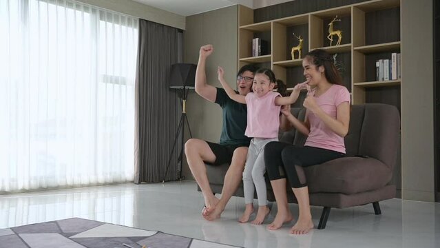 A family holiday where parents and children happily sit and watch sporting events in the living room of the house.