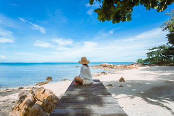 happy woman sitting on wood bridge with view of the sea, soft focus with noise