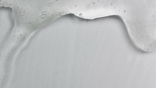 Clean transparent shampoo with bubble flowing from bottom. Macro cosmetic, cleaner texture background, isolated on white