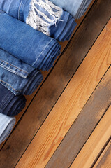 Fototapeta na wymiar Jeans heap at wooden background texture. Blue jeans denim fabric on tabletop