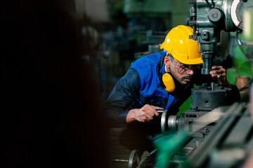 A white male engineer or technician wearing a helmet. Work on maintenance of machinery in industrial factories. Maintenance and Service Concepts production plant