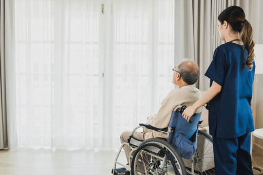 Senior Asian Man In Wheelchair Receives Medical Help For Injury, Take Care And Take To Looking Looking Out Of Window