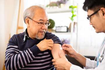 Safe vaccination for old people. Elder man in medical  getting flu or Covid-19 vaccine sitting on...