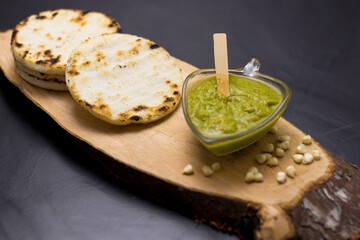 corn arepa traditional Colombian food on top of a log accompanied by sauce