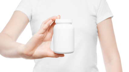 Fototapeta na wymiar Cropped shot of a woman in white t-shirt holding white plastic pill bottle in front of her body, showing it to the camera. Copy space, place for logo or branding.