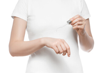Cropped shot of a woman in white t-shirt holding a pipette with serum, isolated on white. Nice short natural nails.