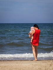 dziewczyna z dzieckiem na ręku na plaży nad polskim morzem bałtyckim