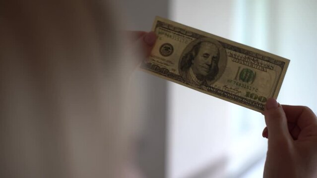 Woman holding dollar bill and looking at it with watermarks closeup.