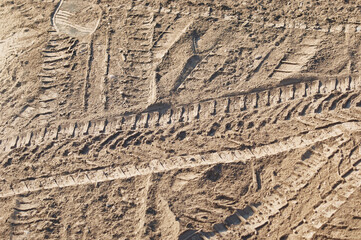 A layer of dry road dust with traces of car tires and shoe soles. Close up.