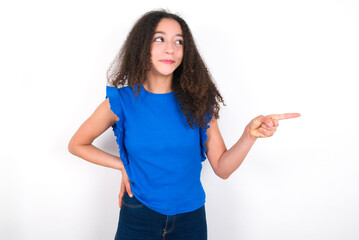 Obraz premium Smiling Teenager girl with afro hairstyle wearing blue T-shirt over white wall indicating finger empty space showing best low prices
