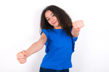 Teenager girl with afro hairstyle wearing blue T-shirt over white wall   imagine steering wheel...