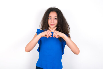 Teenager girl with afro hairstyle wearing blue T-shirt over white wall  Has rejection angry expression crossing fingers doing negative sign.