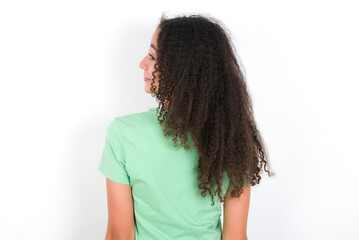 The back side view of a Teenager girl with afro hairstyle wearing green T-shirt over white wall. Studio Shoot.