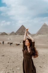 Young redhead tourist girl wearing a brown dress standing on the sand in Egypt, Cairo - Giza....