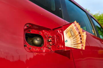 Close up of many fifty euro bills at a car's fuel tank, rising fuel price, paying at the gas...