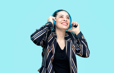 smiling attractive woman listening to music in headphones on blue background