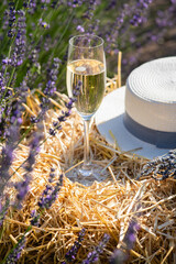 Fototapeta na wymiar A glass of champagne on a bale of hay among lavender