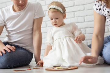 Baby child with hearing aids and cochlear implants plays with parents on floor. Deaf and rehabilitation and diversity concept