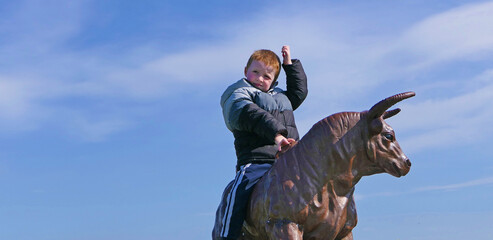 Red headed boy riding a statue Bull in Ireland