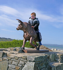 Red headed boy riding a statue Bull in Ireland