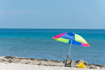 SOMBRILLA Y BOLSO EN LA ORILLA DE LA PLAYA.