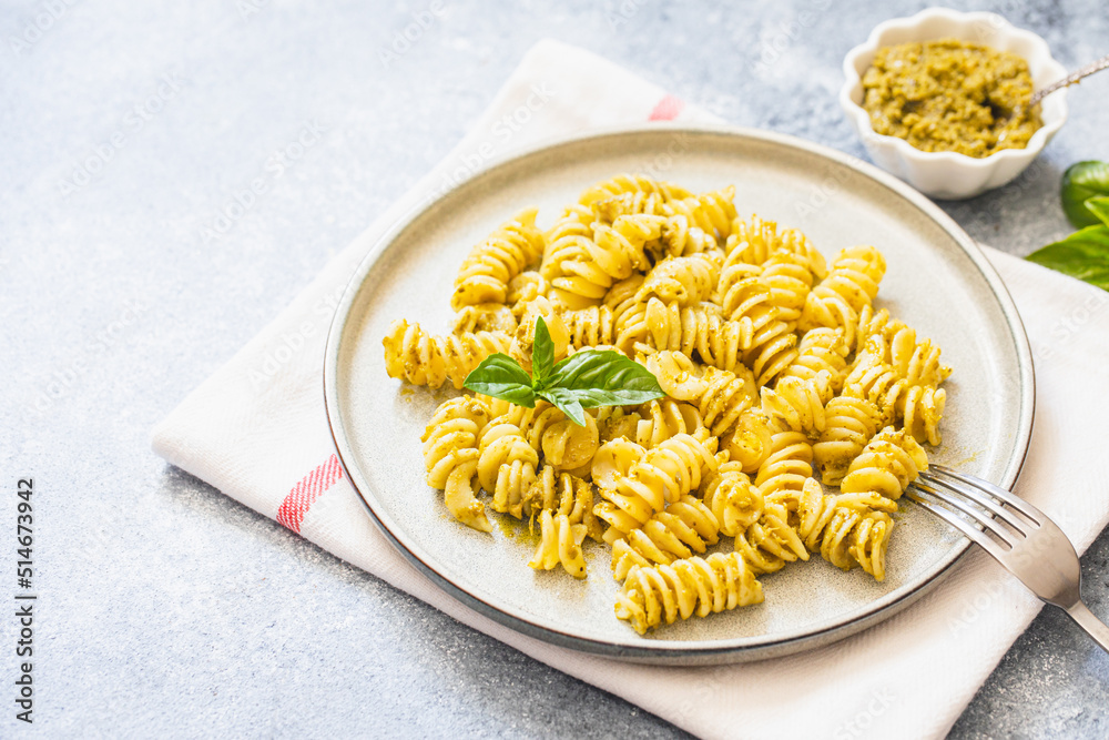 Wall mural fusili pasta with basil pesto and herbs, italian cuisine, gray stone background. Home made food.