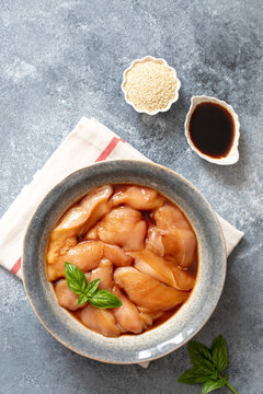 Raw diet marinated chicken meat with teriyaki sauce in a grey bowl. Marinating meat for cooking barbecue
