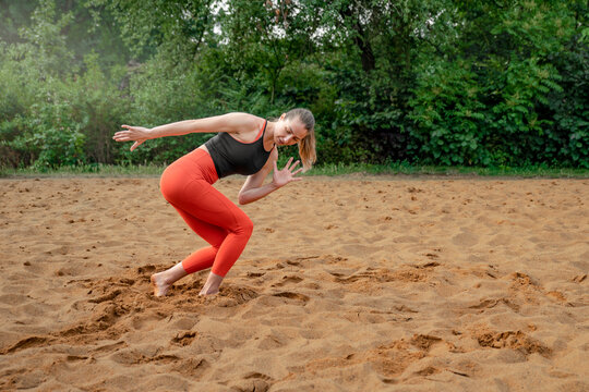 Athletic sexy middle-aged woman, doing fitness barefoot on the sand