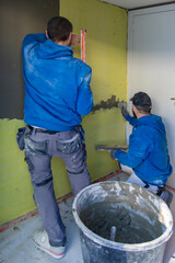 Ouvriers plafonnant les murs intérieurs d’une habitation