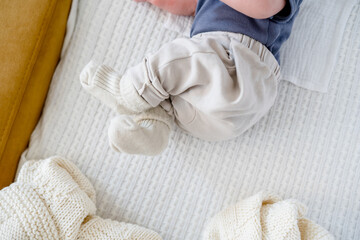 Obraz na płótnie Canvas Baby's legs in warm socks and pants on a white plaid