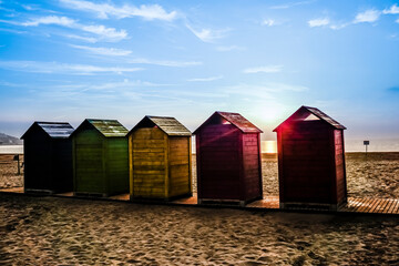 Colorfully painted wooden huts located on the beach by the sea