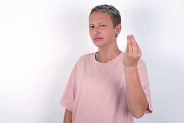 young woman with short hair wearing pink t-shirt over white background Doing Italian gesture with hand and fingers confident expression