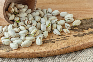 food background of pistachios in a wooden bowl scattered on a wooden board
