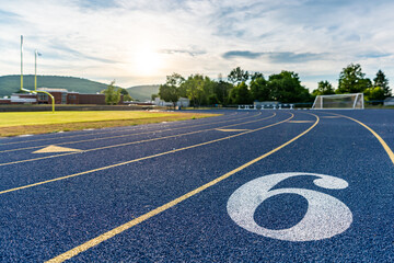 Inspiring close up of a new blue running track with yellow lane lines and other markings.
