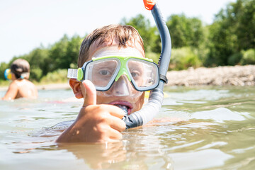 a guy in a diving mask with a snorkel swims in the water - obrazy, fototapety, plakaty