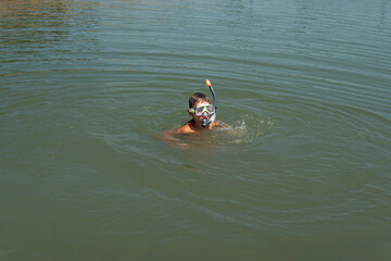 a guy in a diving mask with a snorkel swims in the water