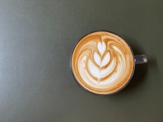 Top view of golden cup with cappuccino on gray background