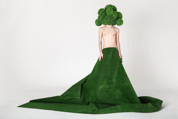 topless young guy wearing a giant green lawn skirt and a huge broccoli mask on his head