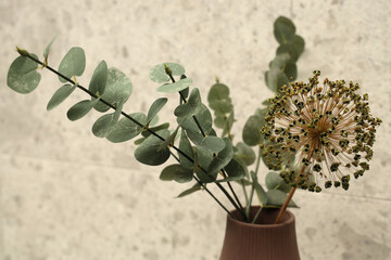 Dry flowers in a vase with leaf in front of stone background