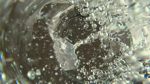 Glass of water. Pure drinking water poured Into glass from jug or jar. Slow motion view from below. Clean water pouring from pitcher into transparent glass. Shot from bottom of glass. Selective focus.