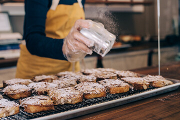 Woman sprinkling powder on some fresh pastry treats